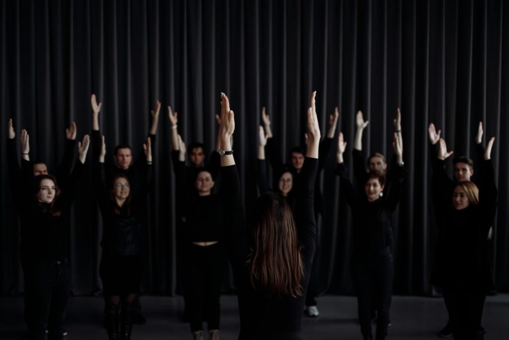 pexels-photo-6194032-6194032 A group of performers rehearsing a contemporary dance with raised arms indoors.